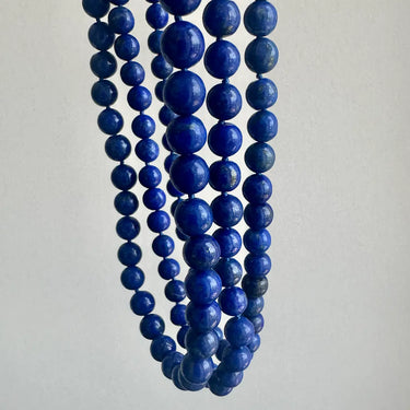 Multiple strands of blue beads on a light gray background