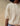 Close up image of a woman wearing a beige knit short sleeve cardigan with white buttons on a tan fabric backdrop.
