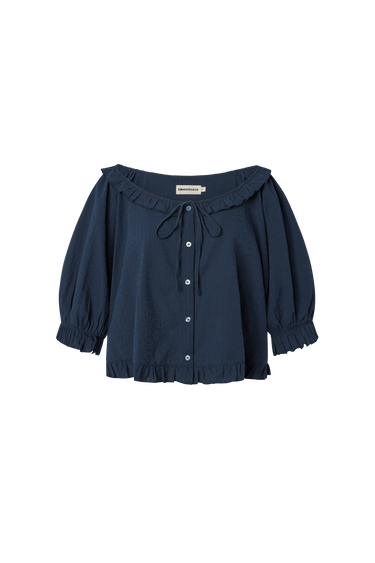 Navy blue eyelet, button-up blouse with a ruffled neckline and short sleeves on a white background.