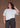 Woman wearing a white t-shirt and black pants against a brown background.