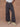 Close-up image of a woman wearing black military-style pants on a tan background.