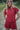 Woman wearing a red outfit with ruffled sleeves and shorts in an outdoor setting.