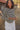 Woman standing in a field, wearing a black and white striped long-sleeved crewneck sweater with a white skirt.