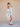 Woman in a light gray outfit with red shoes posing against a beige background