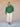 Person wearing a green cardigan and white pants against a beige background