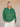 Person wearing a green cardigan against a beige background