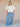 Woman wearing a cream blouse and blue plaid pants against a tan fabric background.