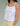Woman wearing a white tank top and yellow pants on a plain background.