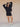 Woman wearing a black v-neck sweater and matching black knit shorts on a tan fabric backdrop.