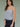 Woman wearing a heather grey tank top and navy blue floral skirt on a plain background.