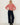 A woman stands against a white wall wearing a red and white striped long-sleeve top, dark wide-leg jeans, and black ankle boots.