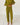 A person wearing a matching olive green knit lounge set consisting of a turtleneck sweater and wide-leg pants, standing barefoot on a white wooden plank floor against a white wall.