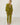 A woman with blonde hair in a ponytail is shown from behind wearing a matching olive green two-piece loungewear set, consisting of a long-sleeve top and straight-leg pants, standing on a light wood plank floor against a white wall.