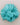 A single artificial flower embellishment in a vibrant turquoise or light blue-green color, made from layered sheer fabric petals, shown on a plain light beige background.