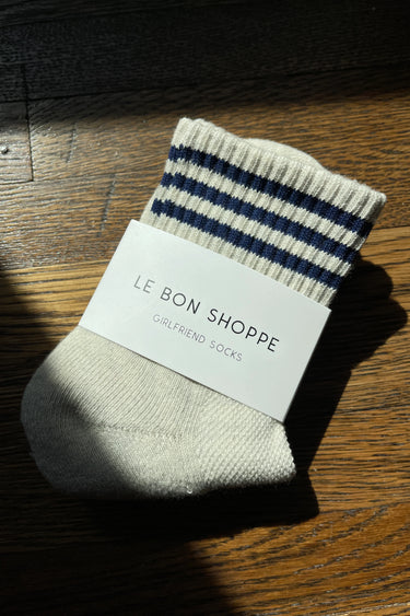 Striped sock with 'Le Bon Shoppe' label on a wooden surface