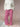 Woman wearing a white cable knit sweater and red gingham pants on a beige background