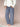 Woman wearing a white cable knit sweater and navy blue and white gingham pants on a beige background.