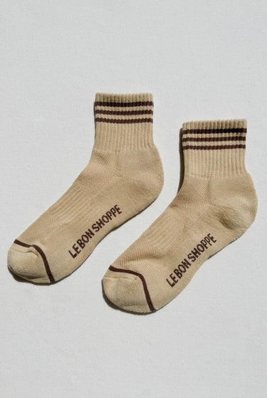 Beige socks with brown stripes and 'Le Bon Shoppe' branding on a light gray background