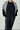 Person wearing a black outfit with a gray cardigan on a white background