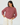 A woman wearing a dusty rose and burgundy horizontally striped long-sleeve sweater with cream pants, standing against a plain white background.