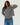 A woman modeling a long-sleeve striped sweater with blue jeans against a plain white studio background.