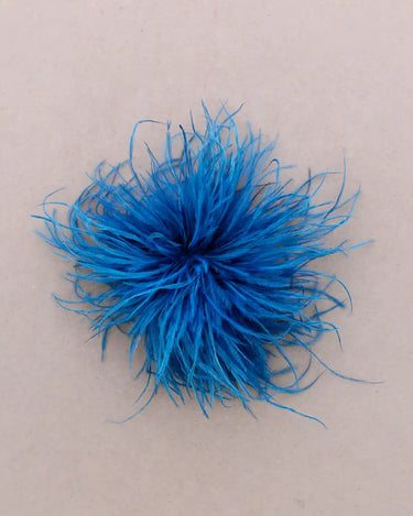 A bright blue feather pom-pom accessory on a plain beige background.