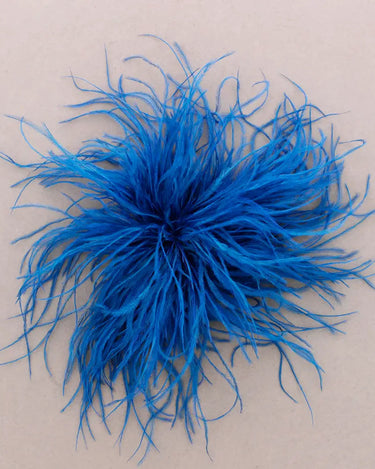 A bright blue feather cluster arranged in a circular burst on a plain beige background.