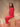 Woman sitting on a wooden block wearing a red, rolled hem sweater and matching red sweater pants.