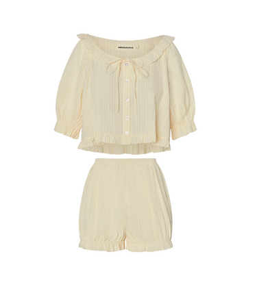 Cream eyelet, button-up blouse with a ruffled neckline and matching bloomer-style shorts set on a white background.