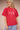 Person wearing a red t-shirt with graphic design on a beige background