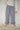 Woman wearing blue plaid casual pants with a ruffled ankle hem against a plain background.