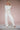 Woman wearing a cream, long-sleeve pointelle top and matching pointelle pants against a pink background.