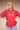 Person wearing a red t-shirt with graphic design on a beige background