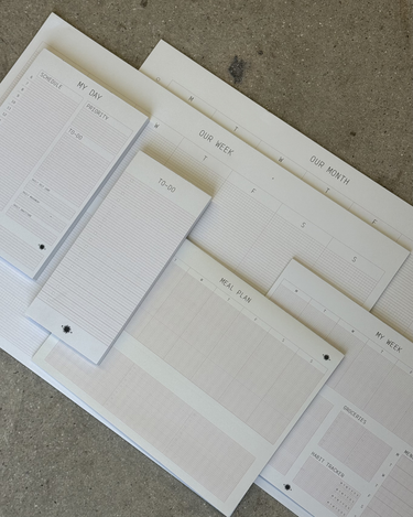 Set of white planner sheets with various schedules and notes on a textured surface
