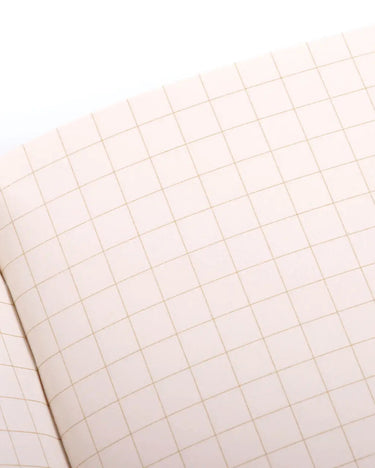 Close-up of a notebook with grid pattern on beige cover