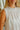 Woman wearing a white sleeveless top with a blurred background