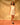 Woman wearing a short white slip dress with thin spaghetti straps and a v-neckline against a tan background.