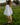 Woman walking in a grassy field outdoors wearing a white eyelet long sleeve blouse and tan skirt.