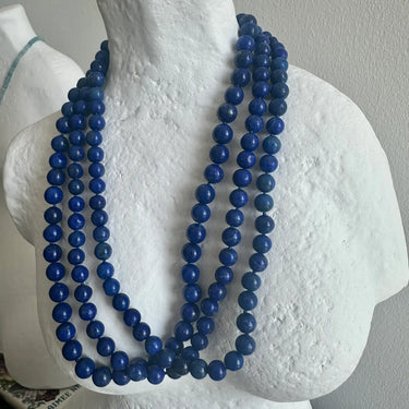 Blue beaded necklace on a mannequin bust against a plain background