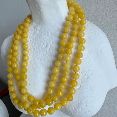 Yellow beaded necklace on a white mannequin bust