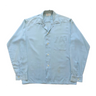 Light blue shirt with open collar on a white background