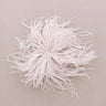 A fluffy beige feather embellishment or brooch, displayed on a neutral beige background.