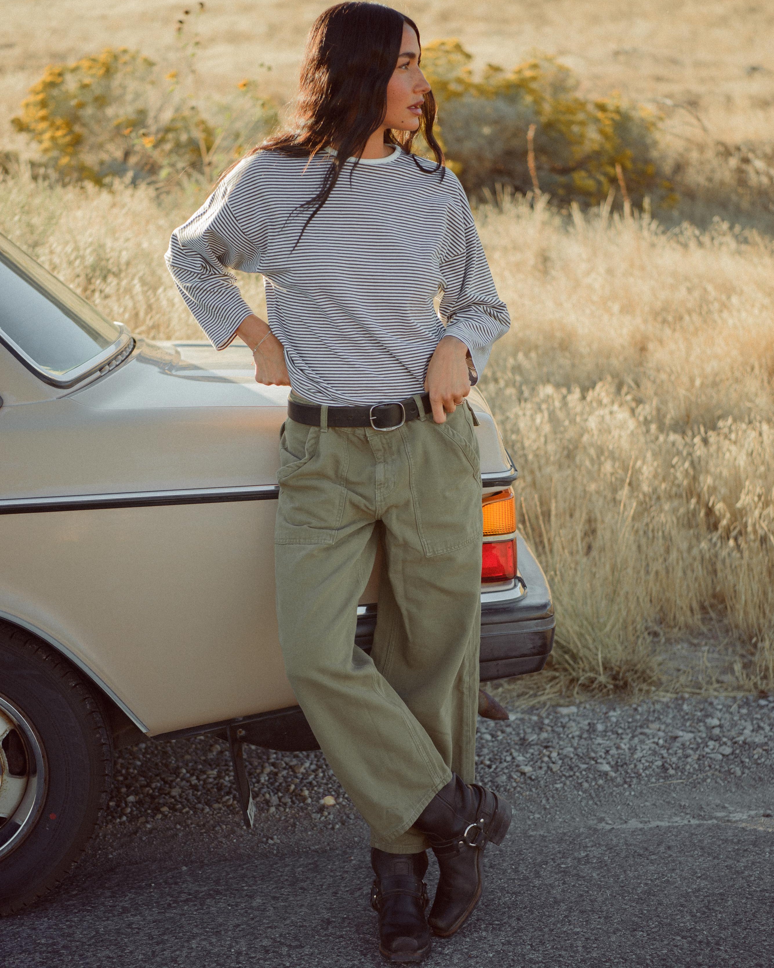 Woman standing next to a vintage car in a desert setting