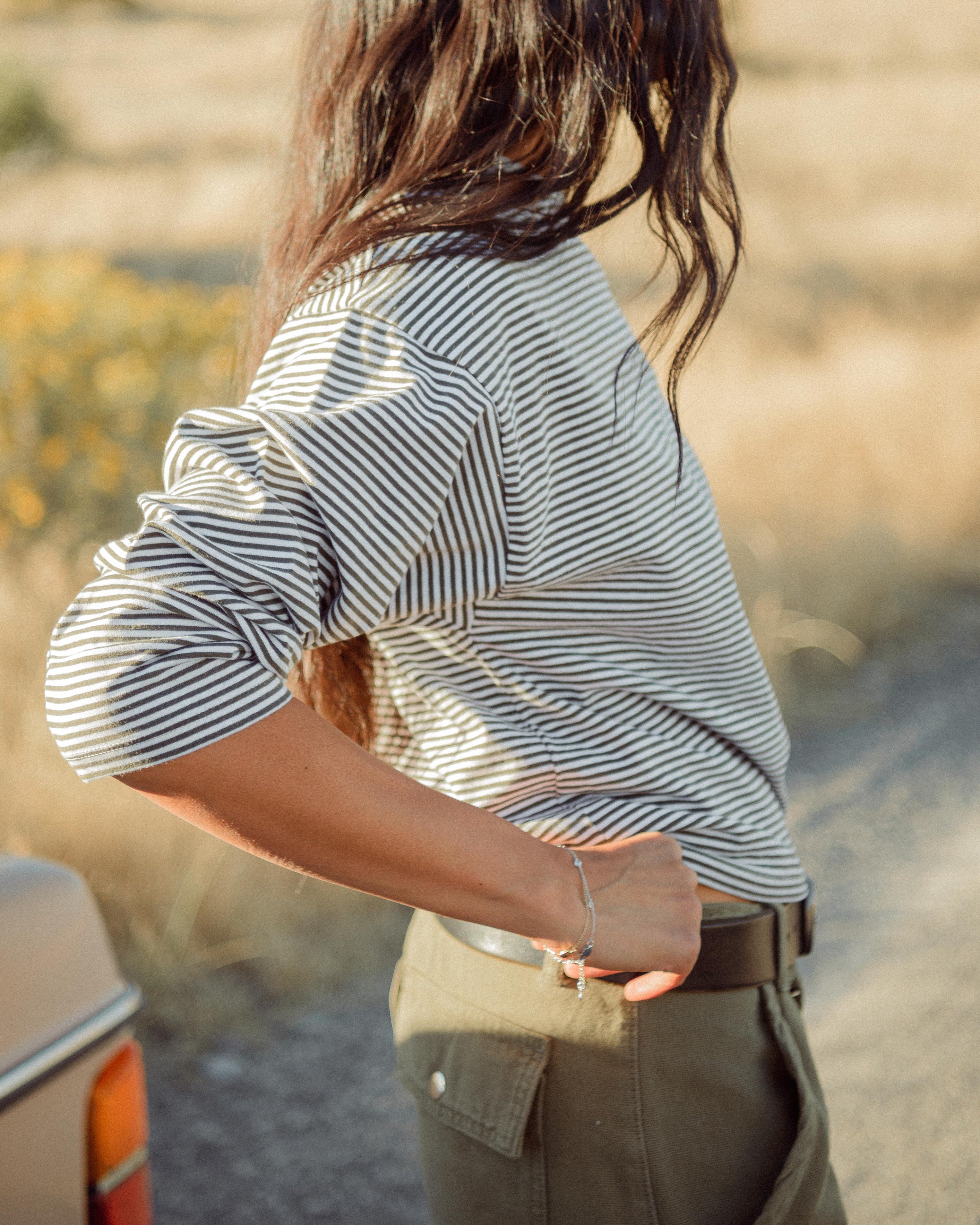 Woman wearing a striped shirt and green cargo pants outdoors.
