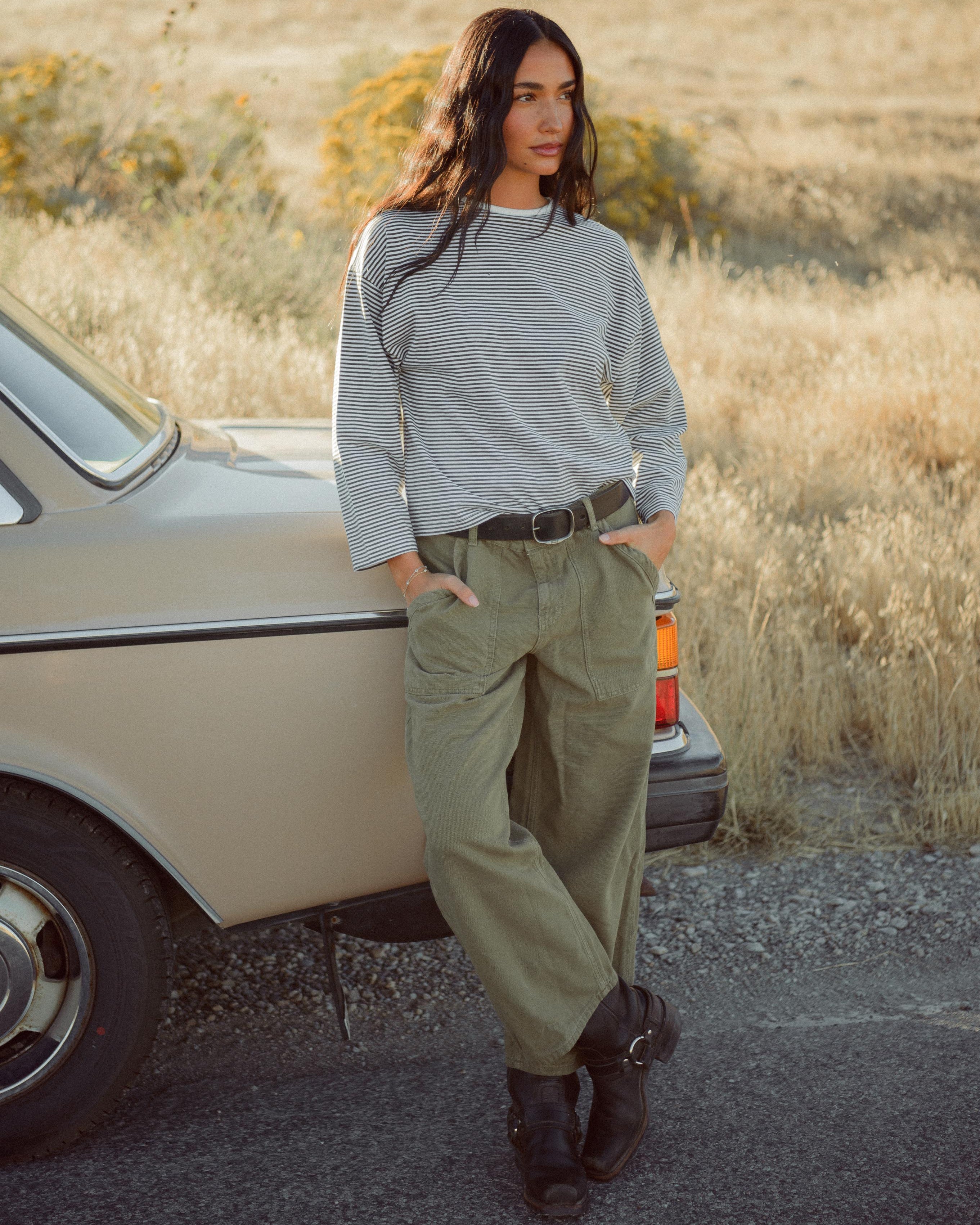 Woman standing next to a vintage car in a desert setting