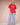 Woman wearing a red t-shirt and blue stripe casual pants with ruffled ankle hem on a plain background.