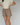 Woman wearing a pair of brown plaid boxer-style shorts with an elastic waistband and ruffle detail at the bottom, paired with a cream shirt.