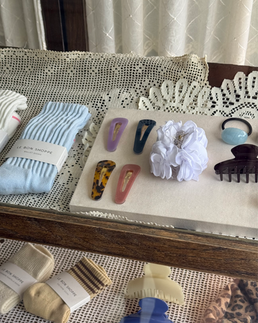 Collection of hair accessories including clips, a scrunchie, and socks on a lace tablecloth.