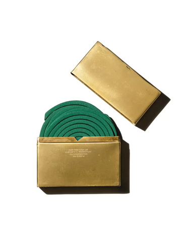 Green circular mosquito coil in a gold holder on a white background