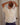 Woman wearing a cream t-shirt and denim pants in front of a door.